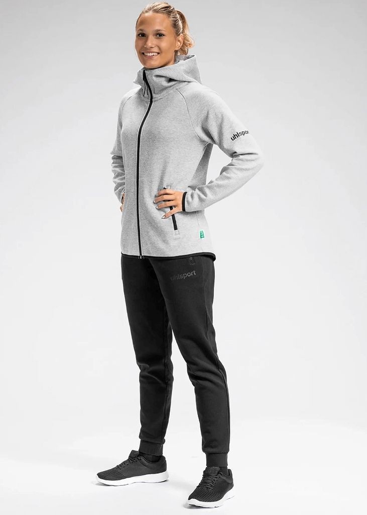 Damski dres sportowy uhlsport id popielato czarny składający się z rozpinanej, jasnoszarej bluzy z kapturem oraz dopasowanych czarnych spodni ze ściągaczami.