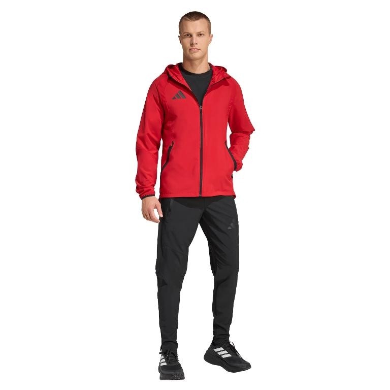Męski dres reprezentacyjny adidas Tiro Travel – czerwona wiatrówka z kapturem i czarne spodnie sportowe z charakterystycznymi trzema paskami adidas.