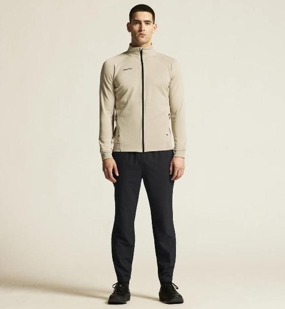 Męski dres tenisowy z linii premium Craft ADV Unify – beżowa rozpinana bluza ze stójką i czarne spodnie sportowe o eleganckim wykończeniu.