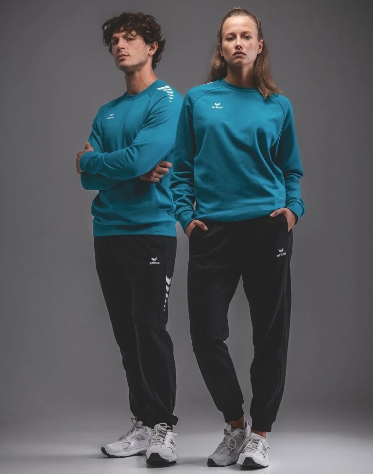 Męski dres bawełniany Erima CMPT Wings – turkusowa bluza wkładana przez głowę z czarnym nadrukiem na ramionach oraz czarne spodnie dresowe.