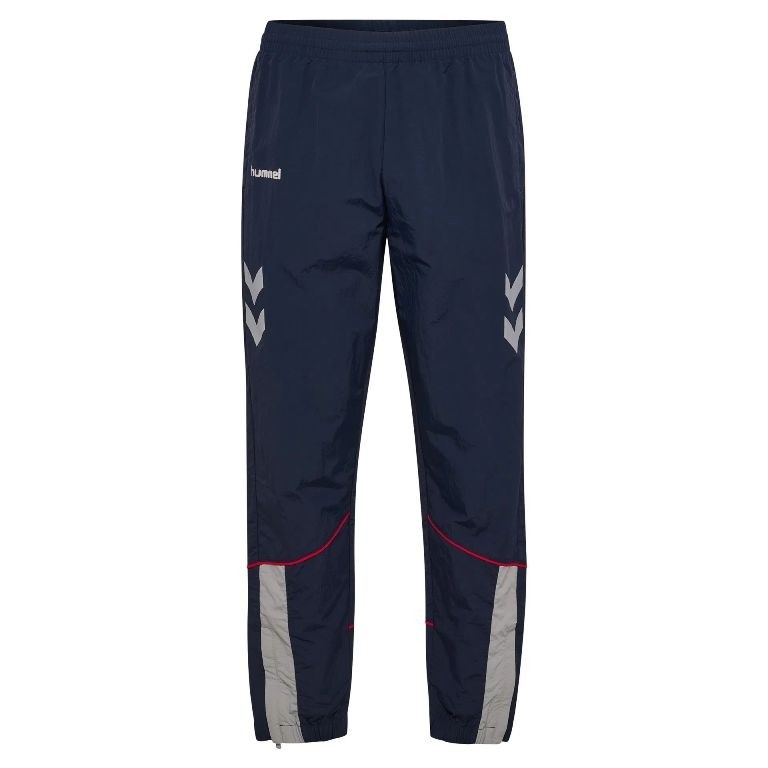 Granatowe męskie spodnie dresowe hummel World 26 z szarymi panelami u dołu nogawek i białymi szewronami na bokach.