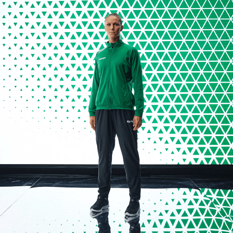 Damski dres treningowy Kempa Ambition 28 – zielona bluza sportowa o taliowanym kroju rozpinana na zamek oraz czarne spodnie dresowe Kempa Lite.