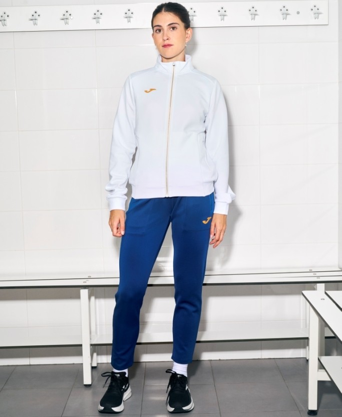 Damski dres tenisowy Joma Confort V – biała rozpinana bluza ze stójką i granatowe spodnie sportowe o dopasowanym do sylwetki fasonie.
