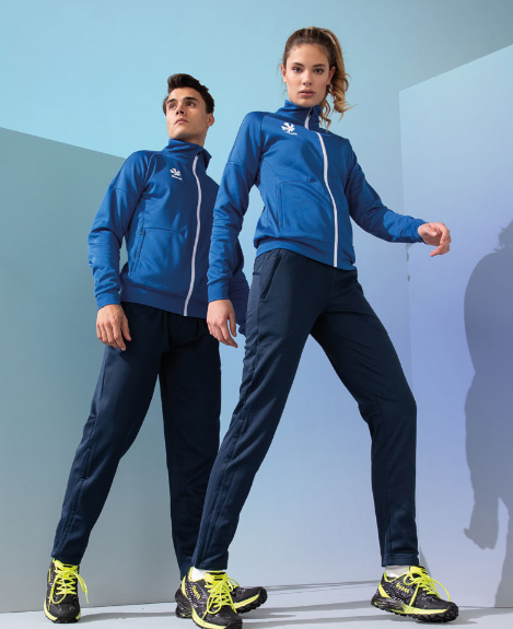 Damski dres sportowy Reece Australia Premium – niebieska rozpinana bluza z białą stójką i logo oraz dopasowane granatowe spodnie dresowe.