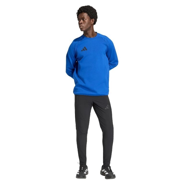 Męski dres bawełniany adidas Tiro Travel – niebieska bluza z okrągłym dekoltem i czarne spodnie dresowe z białym logo adidas.