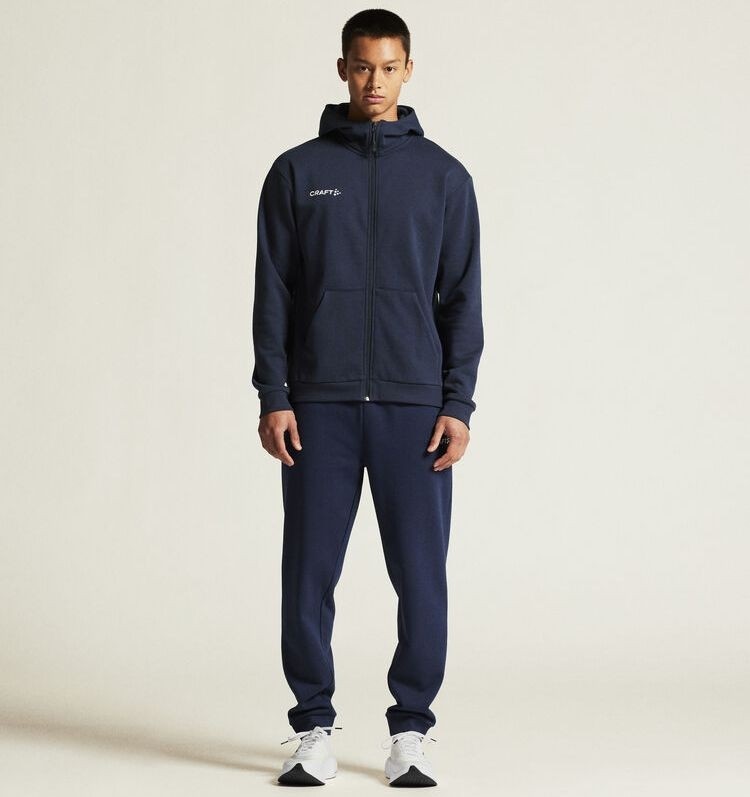 Męski dres bawełniany Craft Community 2.0 – granatowa bluza z kapturem zapinana na zamek oraz dopasowane spodnie bawełniane ze ściągaczami.