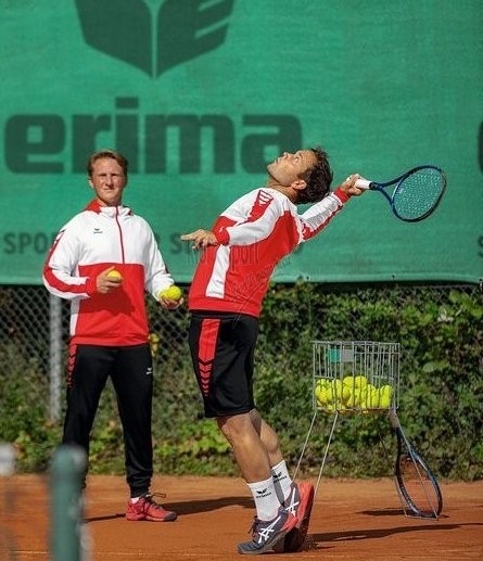 Męski dres tenisowy Erima Six Wings – biała bluza z czerwonymi panelami na ramionach zapinana na zamek oraz czarne spodnie sportowe.