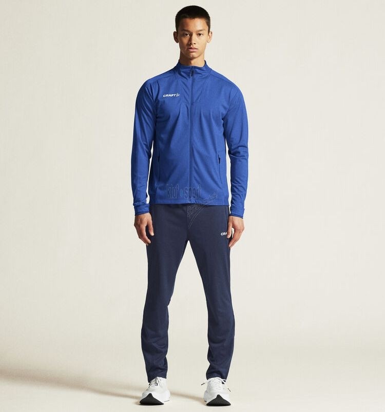 Męski dres sportowy CRAFT Evolve 2.0 – niebieska bluza z pełnym zamkiem (Cobolt) oraz dopasowane granatowe spodnie dresowe (Navy).