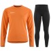 Damski komplet treningowy Craft – pomarańczowa bluza Evolve 2.0 wkładana przez głowę oraz czarne elastyczne legginsy Rush z zamkami przy nogawkach.